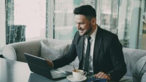 Smiling businessman in a suit looking at his computer while reviewing long term incentive plans