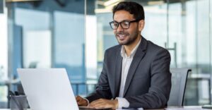 Business professional in a modern office using a laptop, representing how private equity firms leverage technology to scale efficiently.