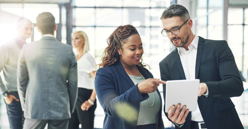 Two business professionals review compensation data on a tablet, symbolizing executive pay planning and strategies for aligning rewards with company goals