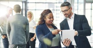 Two business professionals review compensation data on a tablet, symbolizing executive pay planning and strategies for aligning rewards with company goals