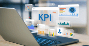 A laptop displaying floating digital dashboards with charts, graphs, and analytics surrounding the large text “KPI,” representing data tracking and performance measurement.