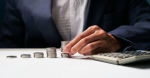 Business professional stacking coins in ascending order beside a calculator, symbolizing structured and scalable variable pay management