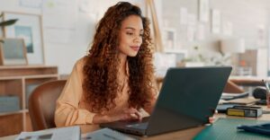 HR professional researching compensation management solution options on a laptop at her office desk