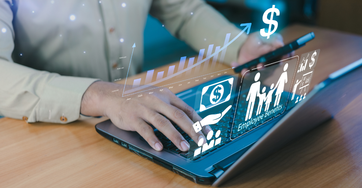 Person in business attire working on a laptop displaying holographic icons for financial growth, employee benefits, and payroll management, with an upward trending chart and dollar sign symbol floating above the screen.