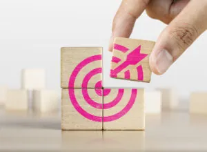 Hand putting the last piece of wooden blocks with the dart target icon