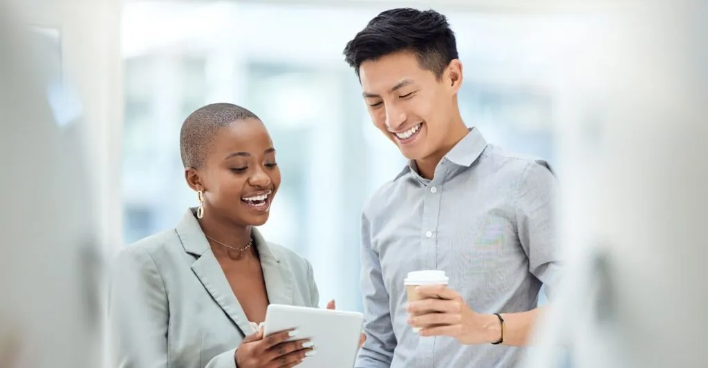 Two smiling employees discussing total rewards on a tablet