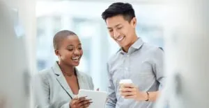 Two smiling employees discussing total rewards on a tablet