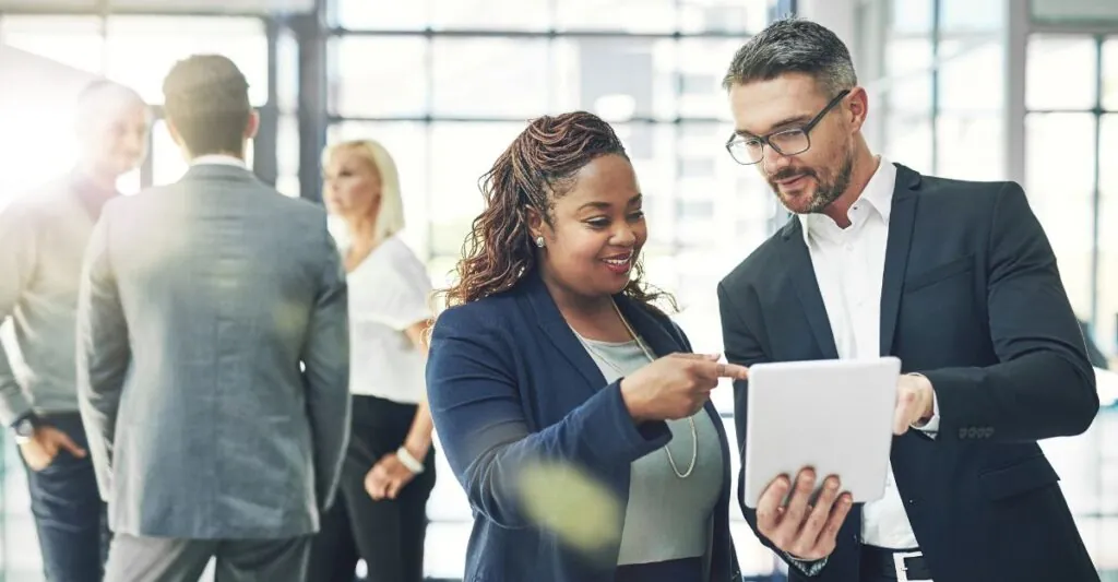 Two business professionals review compensation data on a tablet, symbolizing executive pay planning and strategies for aligning rewards with company goals