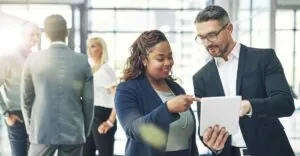 Two business professionals review compensation data on a tablet, symbolizing executive pay planning and strategies for aligning rewards with company goals