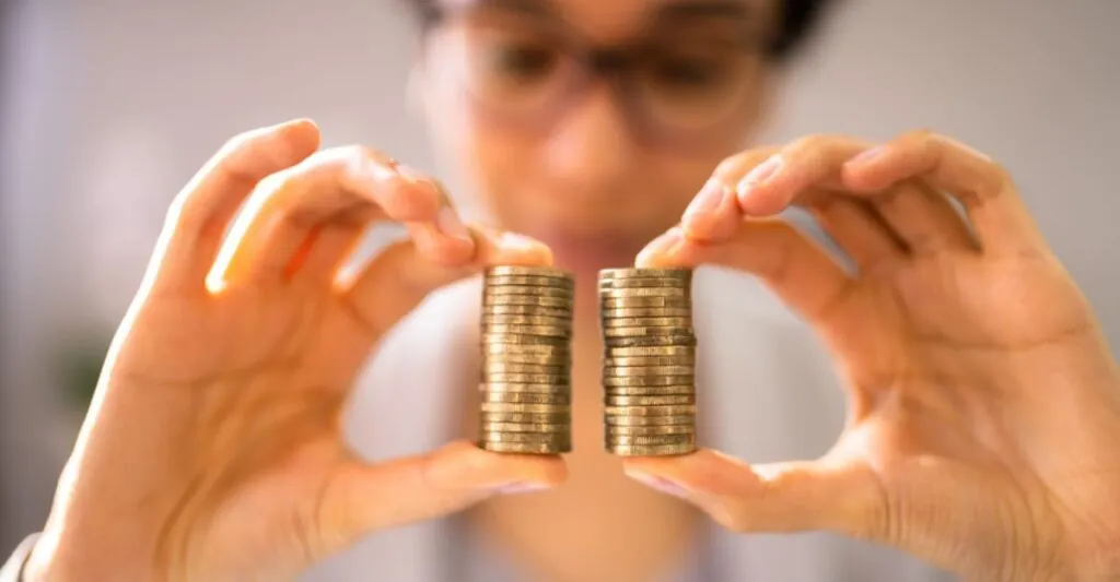 Person comparing two equal stacks of coins, symbolizing pay equity and the EU Pay Transparency Directive 2026.