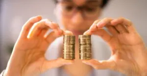 Person comparing two equal stacks of coins, symbolizing pay equity and the EU Pay Transparency Directive 2026.